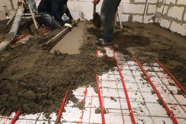 In the newly built house the worker performs a sand-cement screed for heating.2020