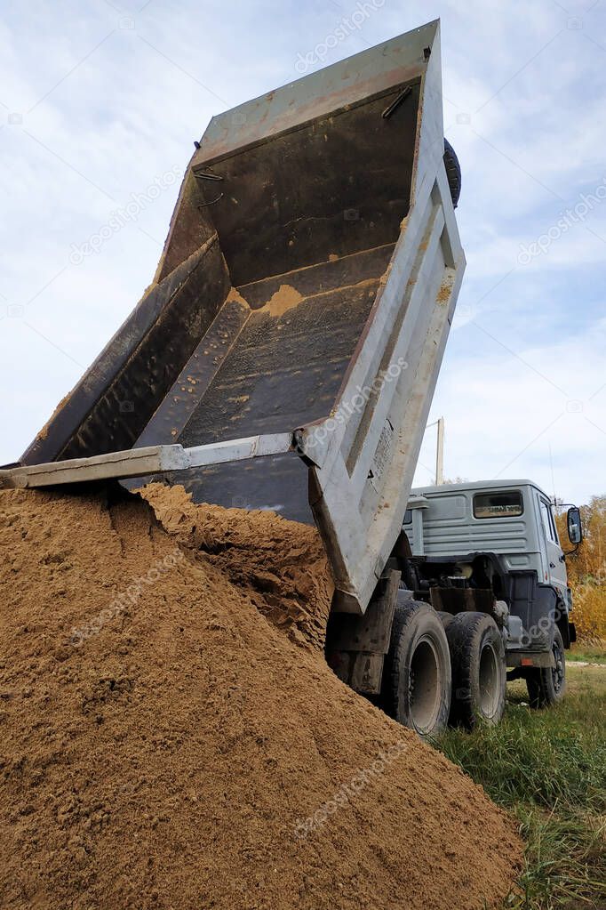 A dump truck unloads sand at a construction site to mix cement.2020