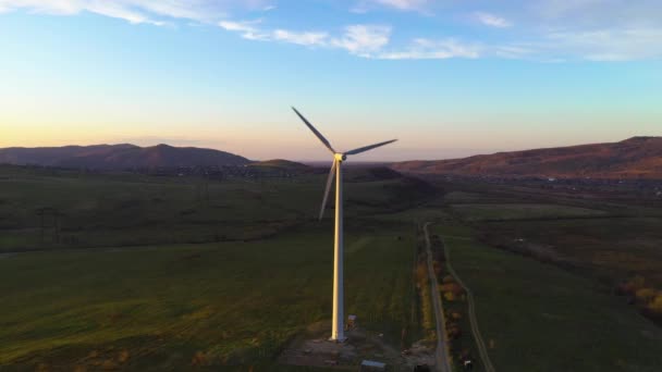 Weiße einsame Windmühle dreht sich bei Sonnenuntergang in den Bergen und erzeugt saubere Energie — Stockvideo
