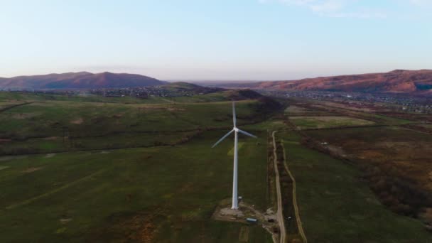 Witte eenzame windmolen draait bij zonsondergang in de bergen en produceert schone energie — Stockvideo