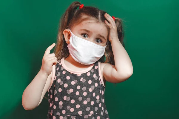 Koncepcyjne Zdjęcie Dziewczynki Masce Medycznej Pokazujące Palec Zielonym Tle Zbliżenie — Zdjęcie stockowe