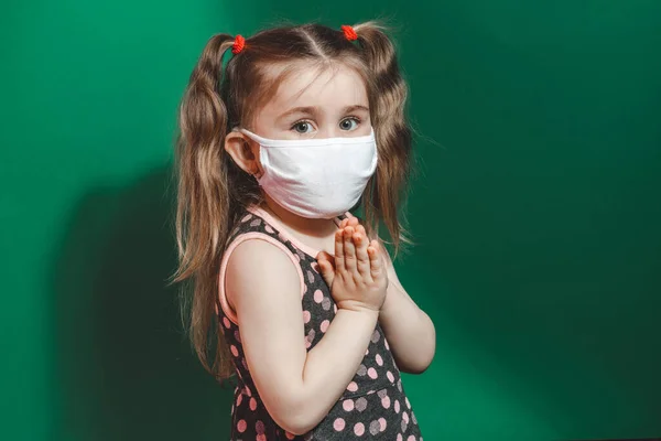 Biała Dziewczynka Masce Medycznej Podczas Epidemii Koronawirusów Modli Się Zielonym — Zdjęcie stockowe