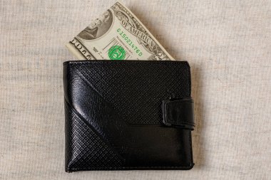 Gri bir arka planda koyu deri bir cüzdanın içinden çıkan 20 dolar.