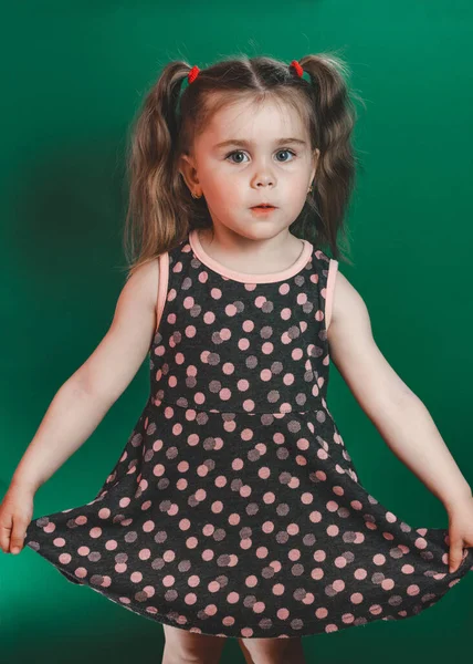 Маленька Дівчинка Трьох Років Хвостами Сукні Позує Студії Зеленому Фоні — стокове фото