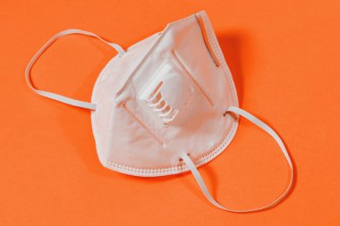 Turuncu arka planda kapakçık ve cerrahi maskeli tıbbi maske 2021