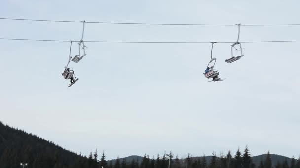 冬季滑雪胜地的人们在雪坡上滑雪和滑雪板。雪山上的滑雪电梯。滑雪胜地的冬季活动 — 图库视频影像