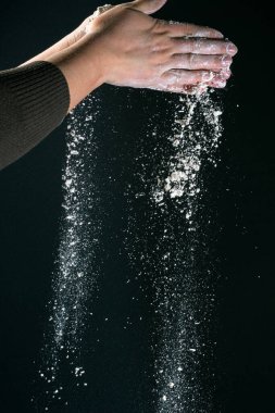 Mutfakta yemek pişiren bir kadının eli, siyah arka planda izole edilmiş ekmek pişirmek için beyaz toz unu un masası döker.