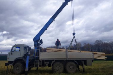 Gökyüzü arka planındaki turna inşaat alanında tahtaları indiriyor. 2020