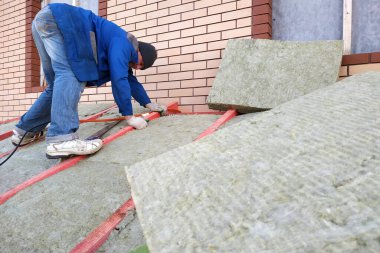 İşçi çatıyı mineral yünüyle yalıtıyor. 2020