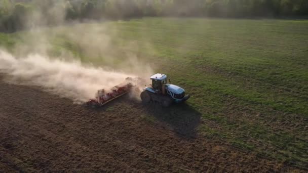 Un tracteur sur chenilles cultive le sol dans un champ agricole. Vue de dessus volant sur un drone. Suivi en cercle. Vidéo 4k .