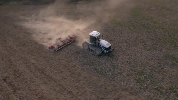 Vue latérale d'un avion survolant un champ cultivé par un tracteur sur chenilles lors d'une crise dans le secteur agro-industriel 