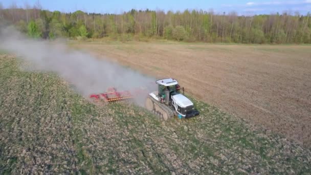 Vue latérale d'un avion survolant un champ cultivé par un tracteur sur chenilles lors d'une crise dans le secteur agro-industriel 