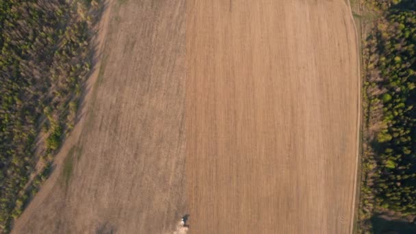 春の播種中にドローンに飛んでいるフィールドのビューの上に、クローラートラクターが経済危機の時に耕運機で土壌を粉砕するとき — ストック動画