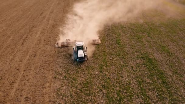 Powyżej widoku pola latającego na dronie podczas siewu wiosną, kiedy ciągnik gąsienicowy mieli glebę z kultywatorem w czasie kryzysu gospodarczego — Wideo stockowe