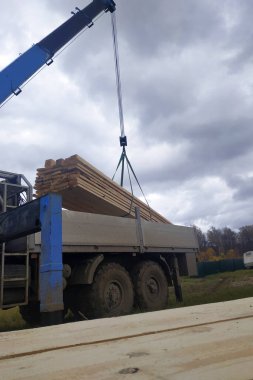 İnşaat alanına vinç, manipülatör ve işçiler tarafından beslenen kargo tahtaları. 2020