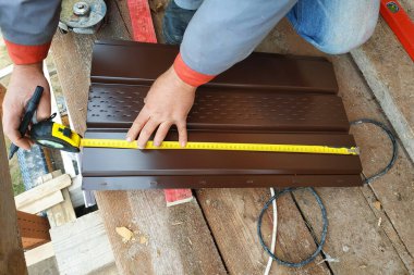 Sihirbaz, kulaklıkları takmak için çatının metal levhasını ölçer. 2020