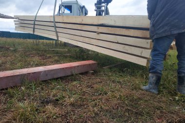 İnşaat alanına vinç, manipülatör ve işçiler tarafından beslenen kargo tahtaları. 2020