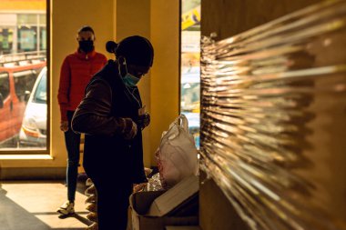 Karantina ve koronavirüs salgını sırasında Avrupa 'da gıda pazarlarının açılması. Siyah Afrikalı öğrenciler 2021 'de koronavirüs salgını sırasında yiyecek alıyorlar. Ivano-Frankivsk, Ukrayna - 25 Mayıs 2020.