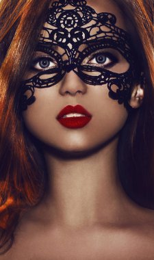 Genç kadın kırmızı dudaklı siyah parti maske takıyor. Siyah dantel maskeyi gözleri üzerine güzel bir kadınla. Koyu tenli kız.