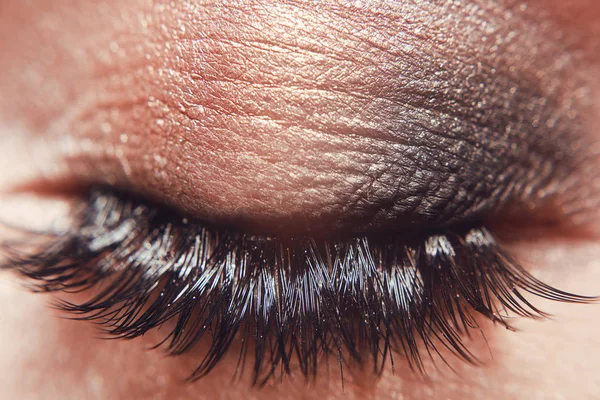 Fashion makeup smokey eyes and cosmetics .Shine earrings . Long Lashes closeup. Beautiful macro shot of female eye with extreme long eyelashes and black liner makeup.Perfect shape make-up,long lashes