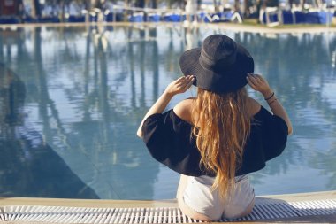 Genç güzel kız siyah moda şapka gülümseme, kadife deri, kırmızı dudaklar, mavi su, şık güneş gözlüğü, Sihir, açık portre, havuzda poz siyah mayo yakın, beackground avuç içi.