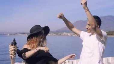 Genç çift okyanus yakın dans / deniz. Tatlı kız eğleniyor ve birlikte açık havada dans balayı çocukla. Âşıklar, dans bir uzun boylu adam kadın güneş gözlüğü ve şapka ile müzik taşımak. Öpücük, kucaklama