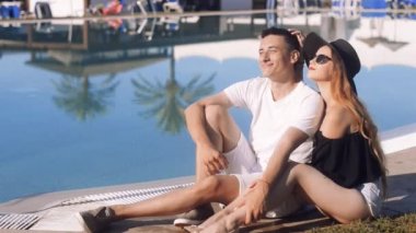 Yüzme Havuzu dinlenme kaygısız severler. Güneş gözlüğü ve şapka kız. Güneşlenme, rahatlatıcı tatil, çift. Beackground avuç içi ve Havuzu. Tatil, turizm, hooneymoon.