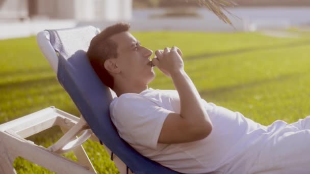 少年はパームに近い電子タバコを吸って Beackgroung パーム 若い男のビーチに電子タバコを吸って Vaping — ストック動画