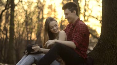 Bir kız ve bir adam parkta oturan, öpüşme, sarılma, On Sunset gülüyor