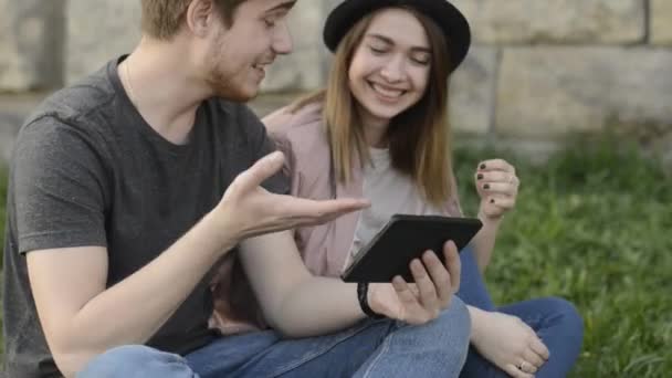 若い男と女は タブレットと笑顔で見てください 若い男と女が楽しんでタブレットで写真を見て — ストック動画