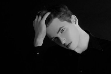 Tek ayakta profil genç yakışıklı ciddi adam kopya alanı ile siyah arka plan üzerinde siyah beyaz görüntü. Mükemmel saç stili olan adam.