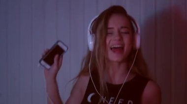 Kız dans kulaklık. Sevimli kız telefonda müzik dinlemek.