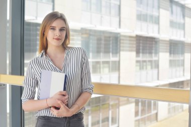 Sırt çantası ve ayakta ve üniversitede, kolaj gülümsüyor not defterleri ile neşeli çekici genç kadın. Kameraya bakarak genç sarışın işkadını veya öğrenci kız. 