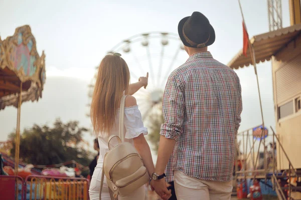 美しい 若いカップルが遊園地で楽しんでいます リラクゼーション愛テーマ公園の概念をデートのカップル 一緒に観覧車の背景にポーズのカップル 観光客は 楽しい時を過す — ストック写真