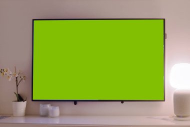 Televizyon masanın üstünde, yeşil arka plan televizyonun üstünde..