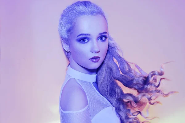 The snow queen in neon. Winter woman in a chic white dress, and snowy white hair. Girl with blue make-up. Winter beauty, stylization. Woman winter, snow, beauty, fashion.