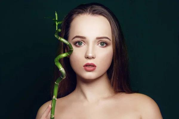 Beautiful portrait of a girl with bamboo in her face on a black