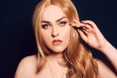 Sarışın, uzun saçlı, kameraya bakıyor. Profesyonel makyaj.