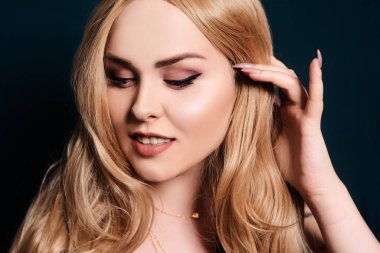 Sarışın, uzun saçlı, aşağı bakıyor. Kafam karıştı. Profesyonel makyaj.