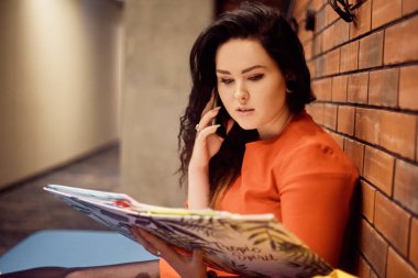 Esmer kız öğrenci, üniversitenin koridorunda oturuyor.