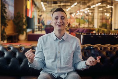 Bir adam oyun oynuyor, elinde bir joystick tutuyor. Bir konsol oyunu