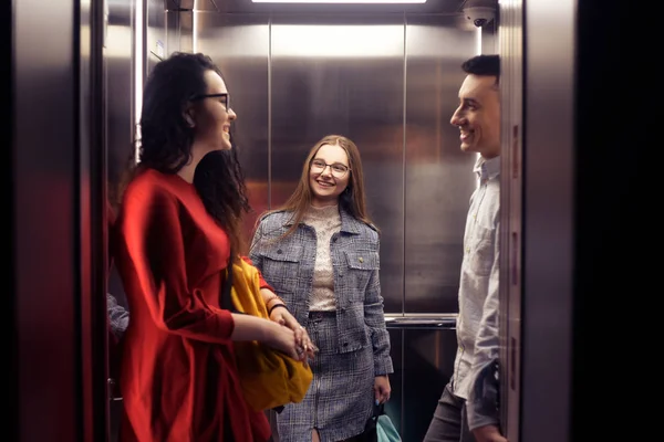 Die Mädchen und der Kerl fahren im Aufzug. Studenten in der elev — Stockfoto