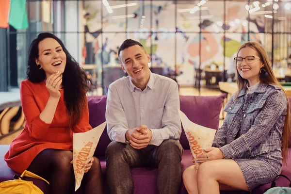 Un groupe de personnes, un mec et 2 filles regardent un film et mangent du popco — Photo