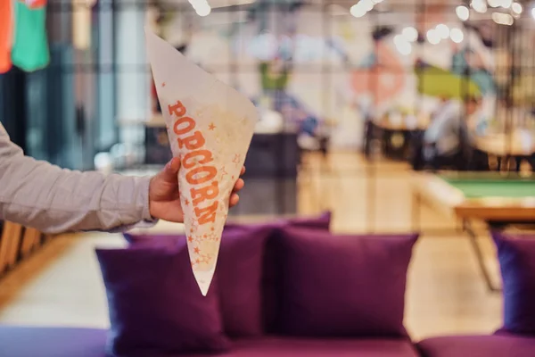 Un homme tient un sac en papier avec du pop-corn sur le fond de la — Photo