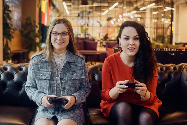 Deux copines jouent à des jeux vidéo, tenant des joysticks dans leur han — Photo
