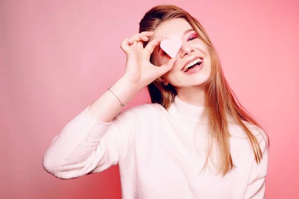 Valentijnsdag, een meisje op een roze achtergrond, sluit haar ogen met — Stockfoto