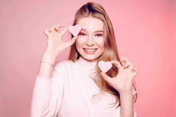 La rubia sostiene un dulce corazón rosado cerca de su cara, en un bac rosado —  Fotos de Stock