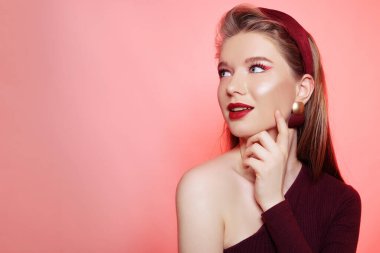 Büyük şapkalı, bordo makyajlı, kırmızı dudaklı, güzel bir sarışın.