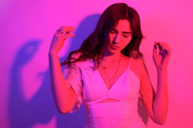 Uzun kıvırcık saçlı, neon rengi dans eden esmer kadın. Profesörü olan bir kız.