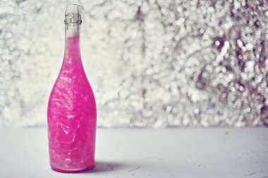 Parlak bir arka planda renkli şampanya. Şampanya pembe gül, arka planda pırıltılar var..